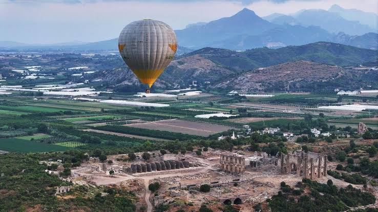 Hot air balloon flight over Aspendos Castle and river at sunrise